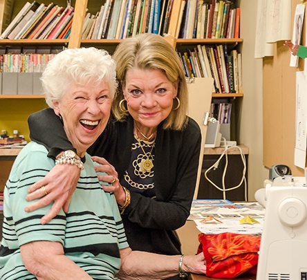 older adult woman hugging senior woman smiling